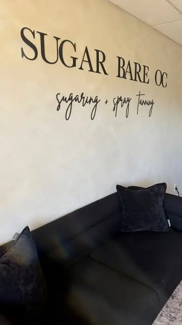 The Sugar Bare OC lobby with the sugaring + spray tanning wall sign